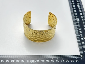 Detail of 18K gold-plated wide cuff bracelet with textured hammered metal surface