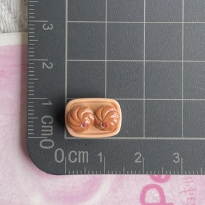 Macro view of miniature food resin bun models on a tray showing size with a scale ruler