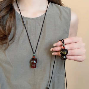 Close-up of cute cat pendants in resin and matte black with colorful beads and woven cords