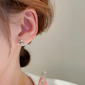 Close-up of model wearing small pearl stud earrings with micro-pave cubic zirconia