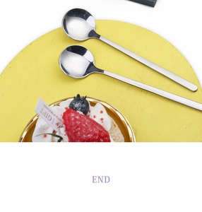 Detailed top view of silver floral coffee spoons on a round yellow wooden board