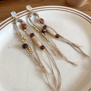 Detail of bohemian tassel earrings with amber beads on a white ceramic plate