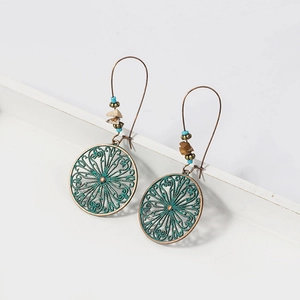 Detail of vintage bohemian bronze earrings with turquoise hollow patterns and natural stones