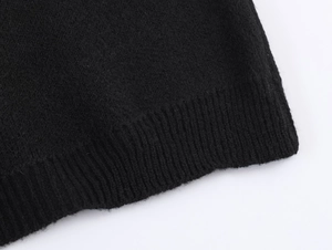 Close-up of black knit fabric showing the fine ribbed texture and detailed hem finishing