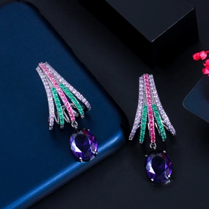 Close-up of fan-shaped silver drop earrings with colorful zircon stones and purple gems
