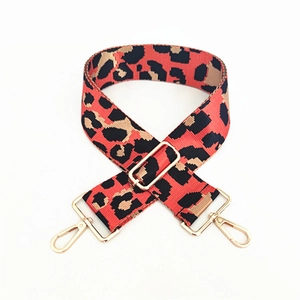 Detail of adjustable leopard print bag strap with red accents and gold hardware