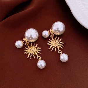 Detailed shot of vintage gold sun earrings with artificial pearls on brown silk fabric