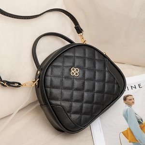 Quilted black PU leather handbag with gold clover charm on a neutral sofa setting