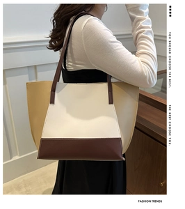 Detail view of a large color-block tote bag in beige, white, and brown leather on model