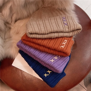 Close-up of four colorful knit beanies with embroidery on a stylish leather stool