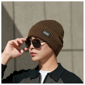 Detail shot of brown ribbed knit beanie featuring an embroidered FUMY text logo patch