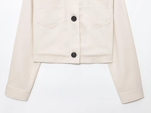 Détail de la veste en lin avec boutons noirs contrastants et rabats de poches symétriques