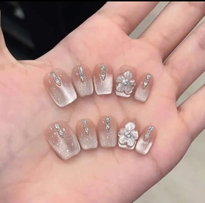 Close-up of cat-eye gradient press-on nails with 3D white flowers and small rhinestones