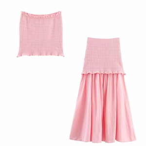Detail of pink two-piece set featuring a smocked bandeau top and a pleated maxi skirt