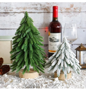 Close-up of mini artificial pine Christmas trees with snow and round wooden bases