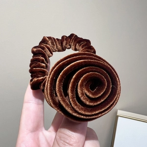 Détail macro d'un chouchou en velours marron avec une fleur en spirale 3D réaliste