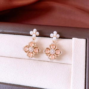 Macro shot of rose gold four-leaf flower earrings with champagne crystals and pearls