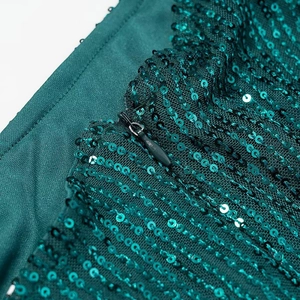 Detailed close-up of the emerald green sequins and hidden zipper on this elegant dress