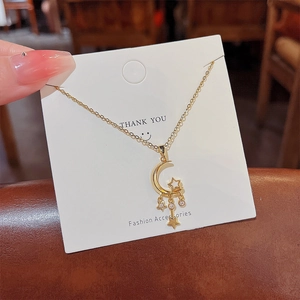 Macro detail of gold star and moon pendant necklace with micro-paved white zircon stones