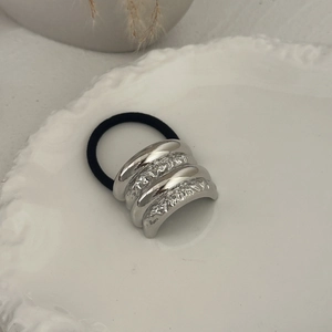 Macro shot of silver metallic tiered ponytail holder hair tie on a white ceramic plate