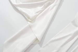 Gros plan sur la texture en soie blanche et les drapés doux du tissu de la robe