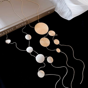 Détail de colliers avec pendentifs ronds minimalistes en or et argent sur un livre
