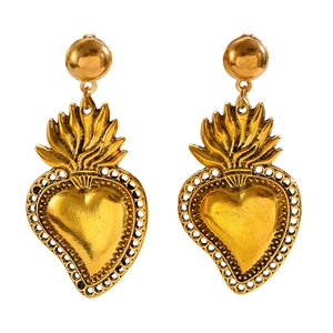 Detail view of vintage gold Sacred Heart drop earrings with hollow lace edges and flames