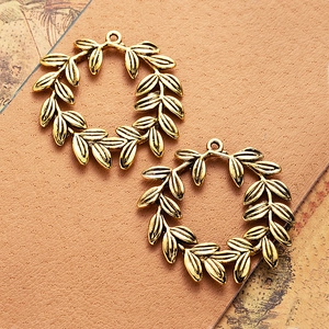Pair of antique gold olive branch pendants on brown leather for DIY jewelry making