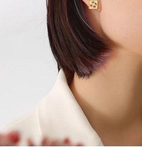 Gros plan de boucles d'oreilles dorées avec cerise rouge portées par un mannequin