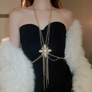 Detail of gold body chain featuring pearl and rhinestone cross pendant with tassels