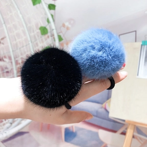 Close-up of soft black and sky blue faux mink fur pom-pom elastic hair ties
