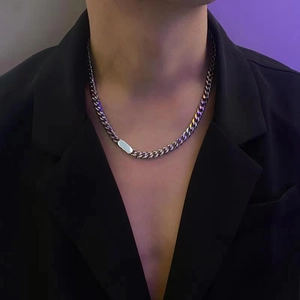 Silver Cuban link necklace with rectangular plaque worn by a model in a black suit