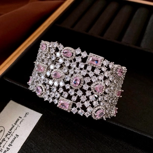 Detail of vintage silver open bangle featuring hollow lace pattern and pink zircons