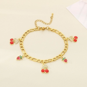 Detail of gold titanium chain bracelet with red cherry and strawberry enamel charms