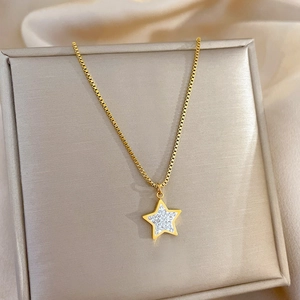 Macro detail of gold pentagram star pendant with cubic zirconia on satin fabric