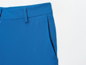 Détail du pantalon bleu vif montrant les passants de ceinture, la poche et les coutures