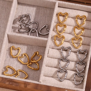 Macro detail of gold and silver hollow heart earrings in a textured jewelry box