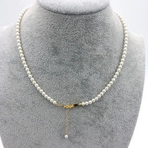 Detail view of round white pearl necklace with adjustable gold-plated lobster clasp