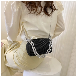 Detail of a cylindrical black rhinestone mini bag with silver chunky chain handle