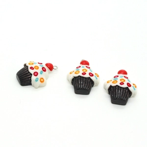Macro detail of three fruit cupcake resin pendants with cherries on a white background