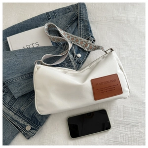 Detail of white nylon crossbody bag featuring geometric wide strap and brown leather patch