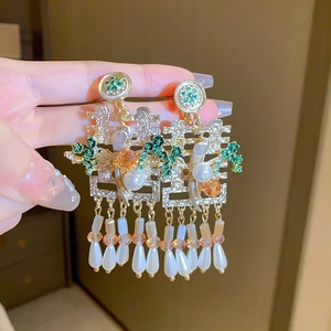 Detail of gold dangle earrings with Xi character, green enamel and pearl tassels