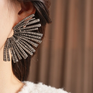 Macro view of large dark grey fan-shaped rhinestone earrings worn on the ear