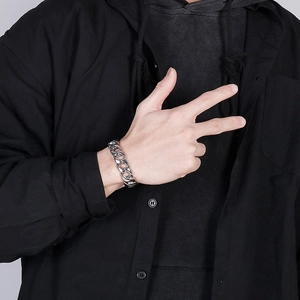 Close-up of a chunky silver stainless steel Cuban link bracelet on a male model wrist