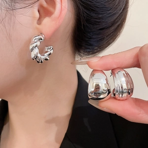 Detailed close-up of silver twist textured hoop earrings and glossy waterdrop studs