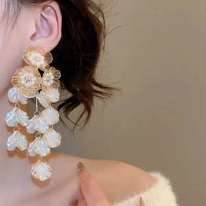 Detail of vintage flower tassel earrings with pearls and gold accents worn by a model