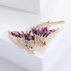 Macro detail of golden phoenix brooch with purple enamel and sparkling crystal inlay