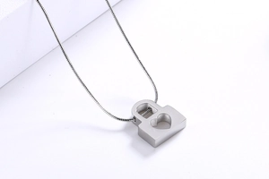Detailed view of silver heart padlock pendant on a sleek snake chain over white decor