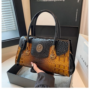 Detail of luxury crocodile embossed leather bag with gradient color and golden emblem
