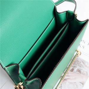 Dettaglio della borsa in pelle verde con scomparti interni e trama martellata